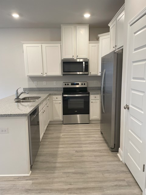 A kitchen with white cabinets and a stainless steel refrigerator.