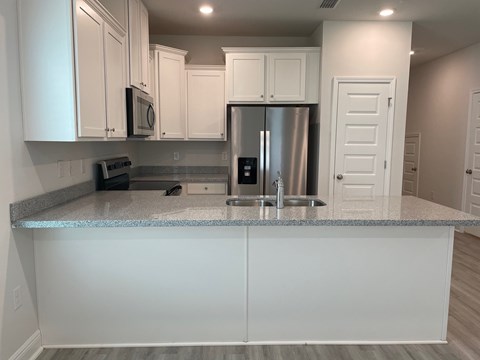 A kitchen with white cabinets and a granite countertop.