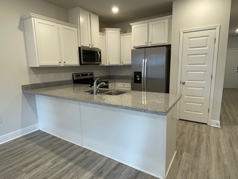 A kitchen with white cabinets and a granite countertop.