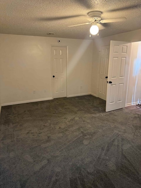 A room with a carpeted floor and two doors.