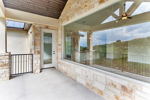 A balcony with a glass railing and a ceiling fan.