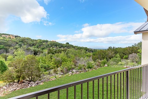 A balcony overlooks a lush green hillside.