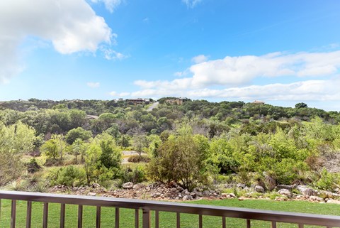 A view from a balcony overlooking a lush green landscape.