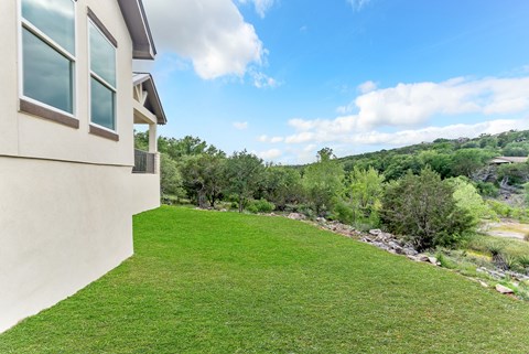 A house with a green lawn and trees in the background.