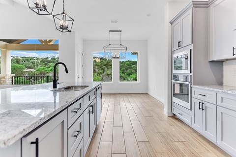 A kitchen with a marble countertop and wooden flooring.