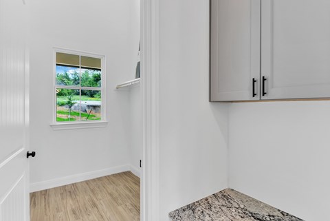 A white room with a window, a door, and a bench.
