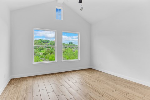 A room with two windows showing a view of greenery outside.