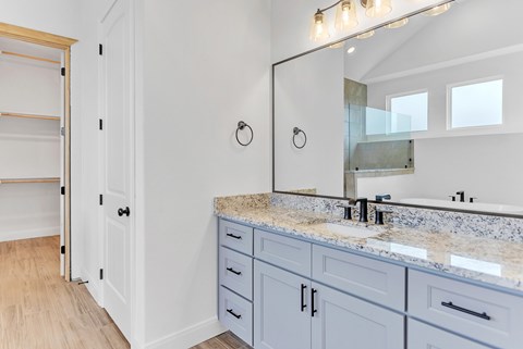 A bathroom with a sink, mirror, and wooden floors.