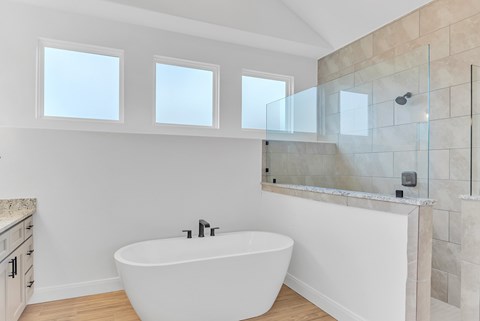 A white bathroom with a tub and a glass shower door.