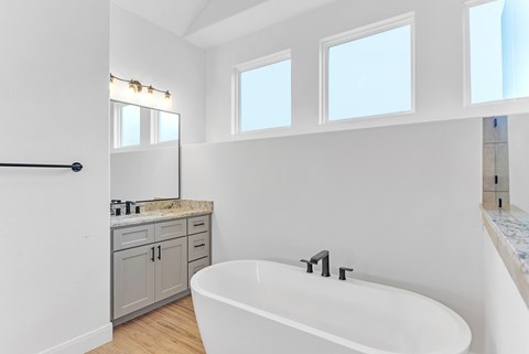 A white bathroom with a tub, sink, and a vanity.