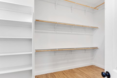 A white closet with shelves and a black door knob.