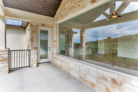A balcony with a glass railing and a ceiling fan.