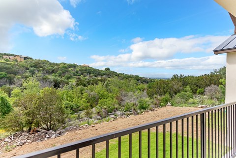 A balcony overlooks a lush green hillside.