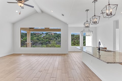A spacious room with a ceiling fan and a view of a green landscape through a large window.
