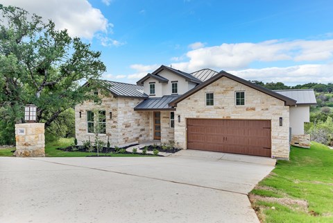 A house with a brown garage door and a stone exterior.