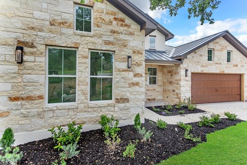 A house with a stone exterior and a brown garage door.