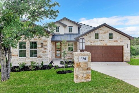 A house with a stone wall and a black garage door.