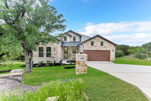 A house with a stone facade and a brown garage door is numbered 380.
