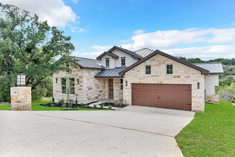 A house with a brown garage door and a stone exterior.