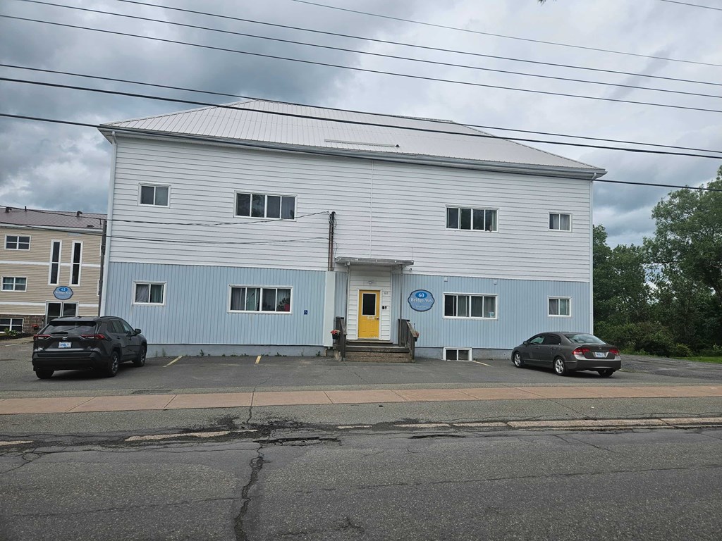 A large white building with a yellow door and a blue sign on the front.