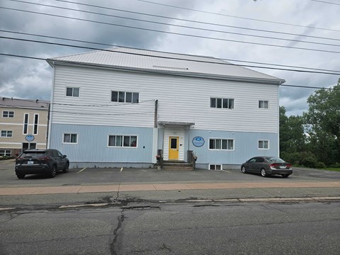 A large white building with a yellow door and a blue sign on the front.