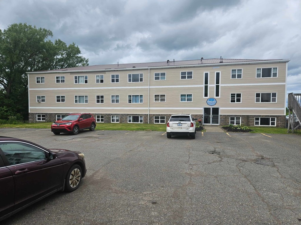 A building with a blue sign on the front and cars parked in front.