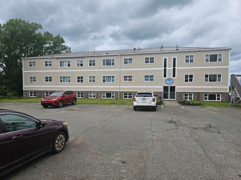 A building with a blue sign on the front and cars parked in front.