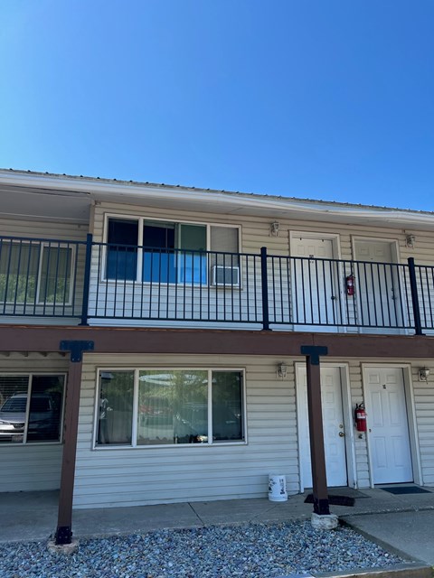 A two-story house with a balcony and a fire extinguisher on the door.