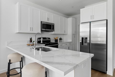 A kitchen with white cabinets and a marble countertop.