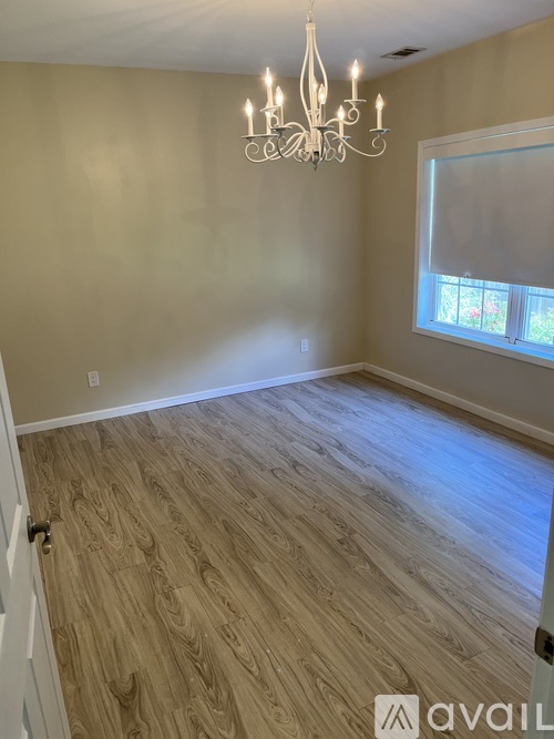 A room with wooden flooring and a chandelier.