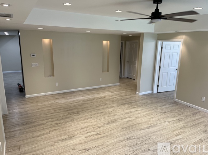 A spacious room with a ceiling fan and lighting fixtures.