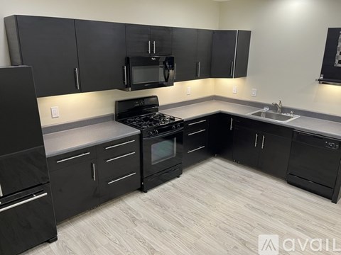 A kitchen with black cabinets and appliances.