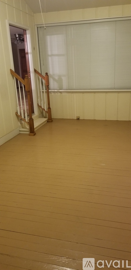 A room with wooden floors and a window with blinds.