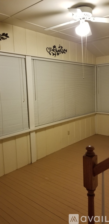 A room with a ceiling fan and wooden flooring.
