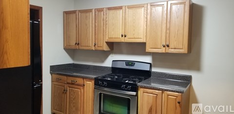 A kitchen with wooden cabinets and a black refrigerator.