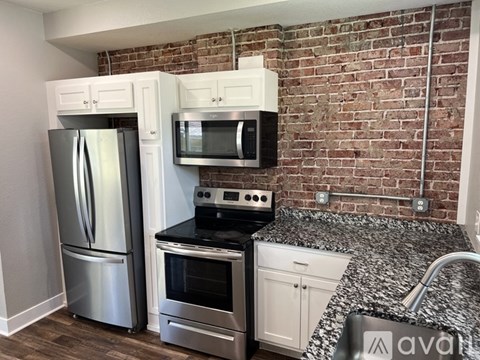 A kitchen with a stainless steel refrigerator and microwave above a stove.