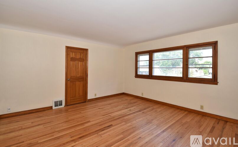 A room with wooden flooring and a window with a view of trees.