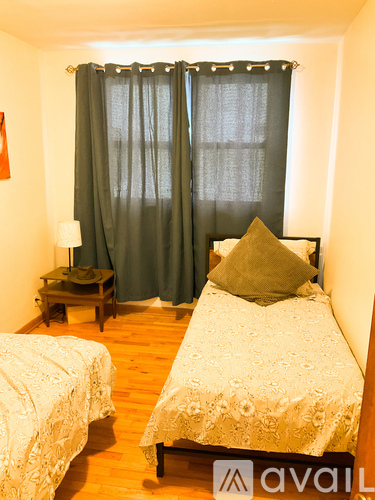 A bedroom with two beds and a nightstand with a lamp.