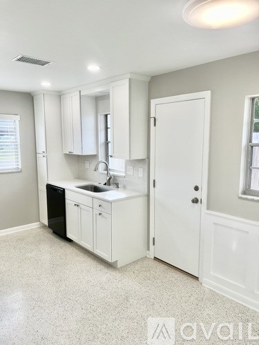 A kitchen with white cabinets and a black dishwasher.