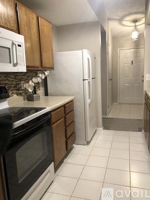 A kitchen with a black stove top oven, white microwave, and a white refrigerator.