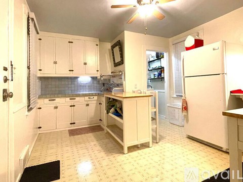 A kitchen with white cabinets and a white refrigerator.