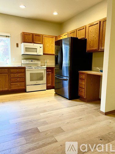 A kitchen with wooden cabinets and a black refrigerator.