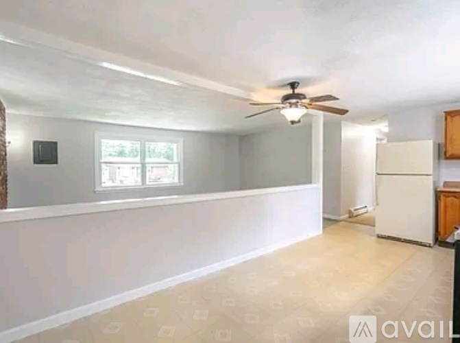 A room with a ceiling fan and a refrigerator in it.