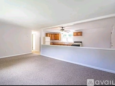 A spacious room with a carpeted floor and a ceiling fan.