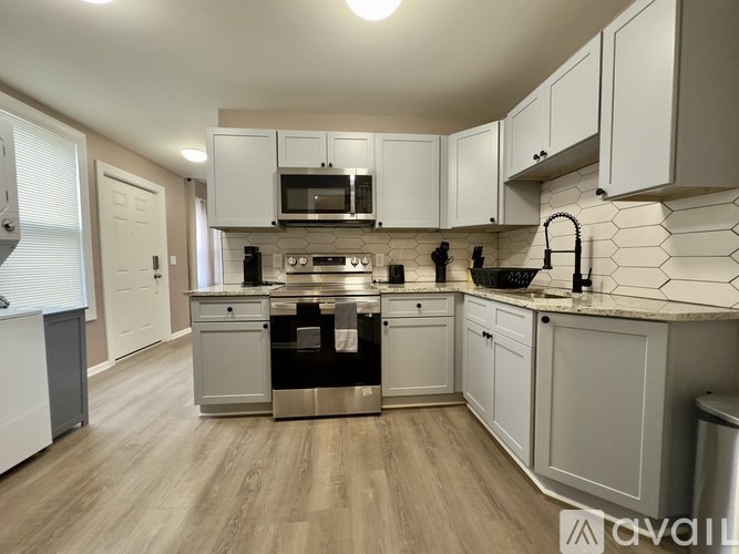 A kitchen with white cabinets and a wooden floor.