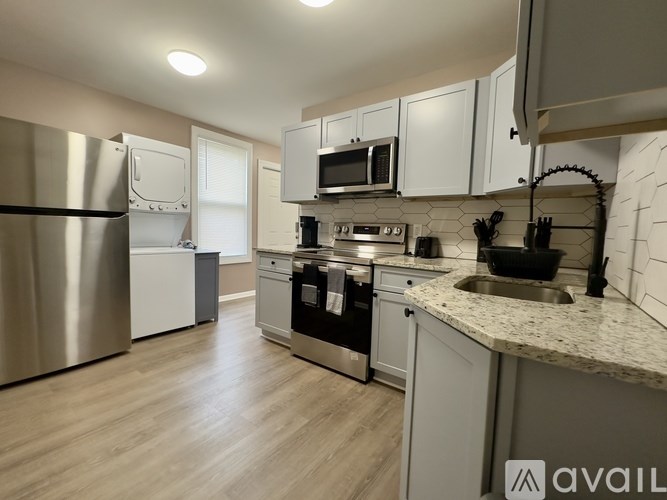 A kitchen with a refrigerator, microwave, oven, and sink.