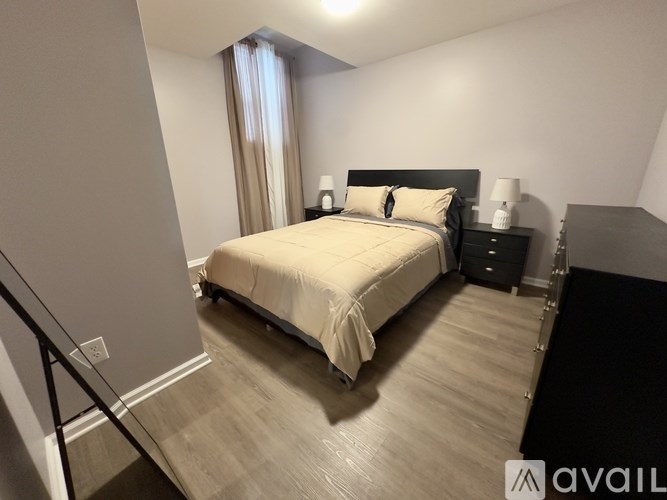 A bedroom with a large bed and a nightstand with a lamp.