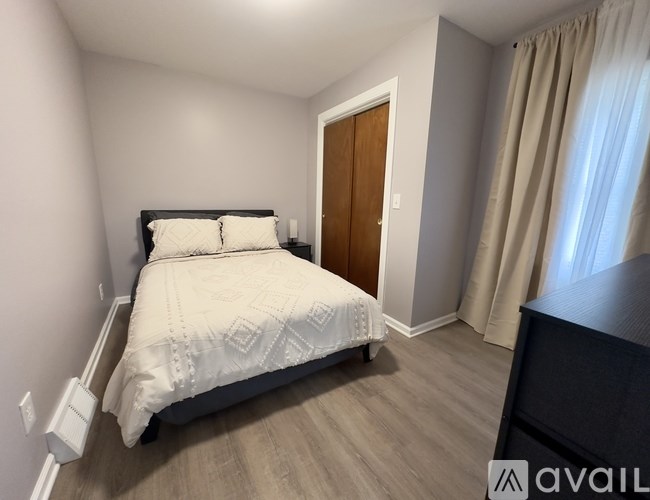 A bedroom with a bed, nightstand, and window.