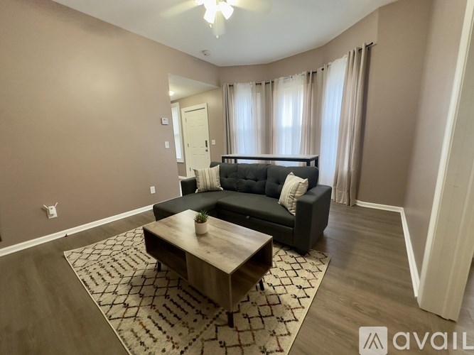 A living room with a black couch and a wooden coffee table.