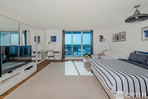 A bedroom with a large bed and a balcony overlooking the city.